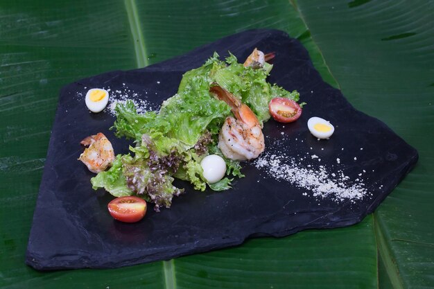 Camarones fritos con lechuga sobre una piedra negra en lugar de plato