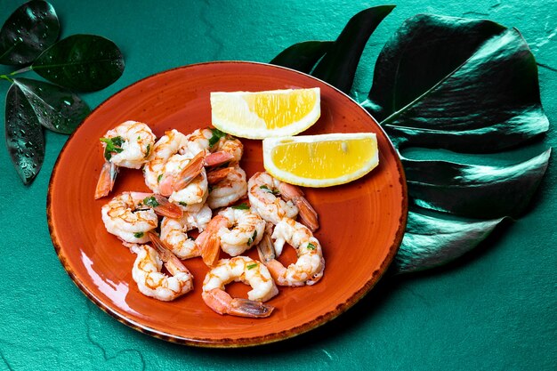 Camarones fritos con limón sobre una placa roja y verde monstera dejar, cerrar