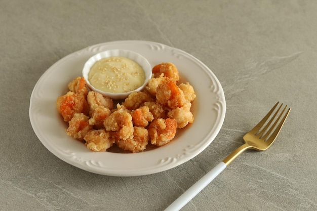 Camarones fritos con mayonesa servidos en plato blanco con tenedor