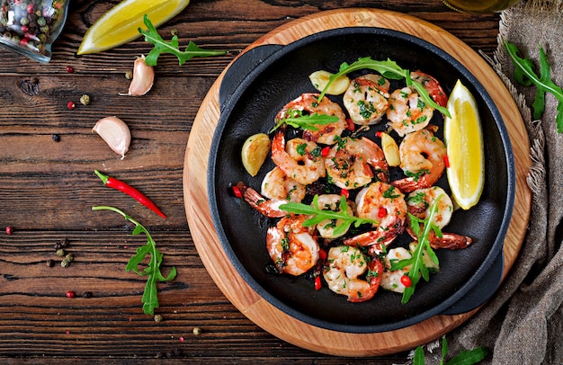 Los camarones de las gambas asaron en mantequilla de ajo con el limón y el perejil en fondo de madera.