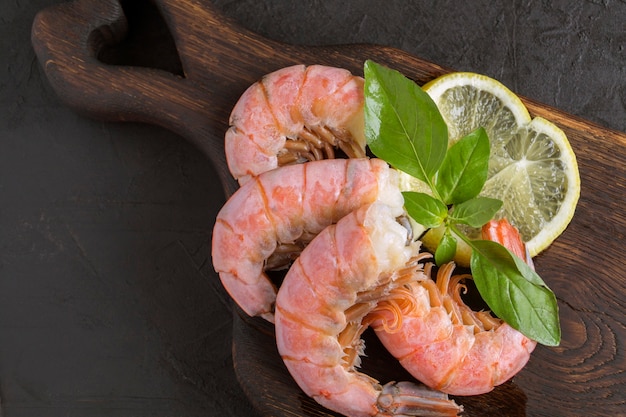 Camarones hervidos con limón sobre una tabla de madera.