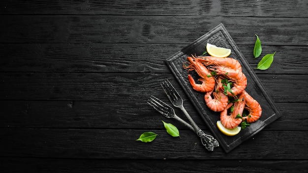 Camarones hervidos con perejil y limón en un plato de piedra negra Vista superior Mariscos