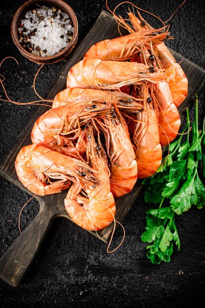 Camarones hervidos en una tabla para cortar con perejil y especias