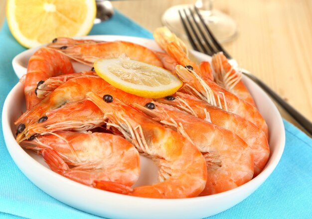 Camarones con limón en plato sobre mesa de madera closeup