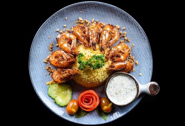 Camarones a la parrilla con arroz frito y verduras en un plato azul aislado en la vista superior de fondo negro