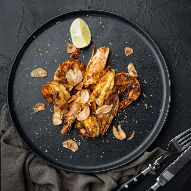 Camarones a la parrilla grandes con salsa de mango dulce y curry, en un plato, sobre negro