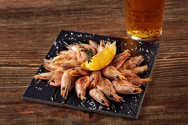 Camarones a la parrilla en pan de pizarra negra y cerveza en la mesa de madera