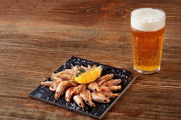 Camarones a la parrilla en pan de pizarra negra y cerveza en la mesa de madera