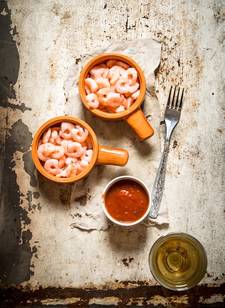 Camarones pelados con salsa de tomate en mesa rústica.