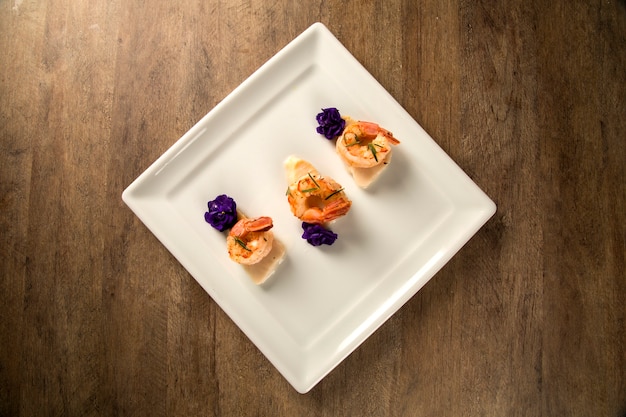 Camarones a la plancha con pescado crudo de uñas en un plato blanco en la mesa