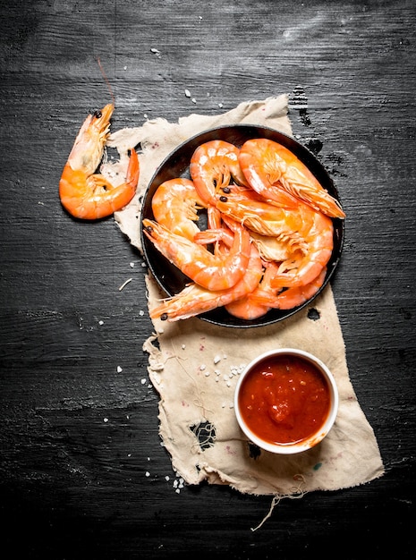 Camarones con salsa de tomate sobre la tela vieja en la pizarra negra