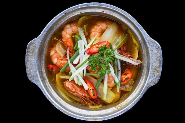 Camarones con verduras en caldo aislado en la vista superior de fondo negro