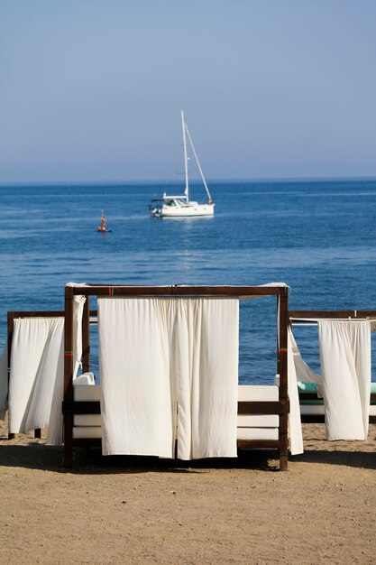 Camas balinesas en playas mediterráneas con catamarán de fondo