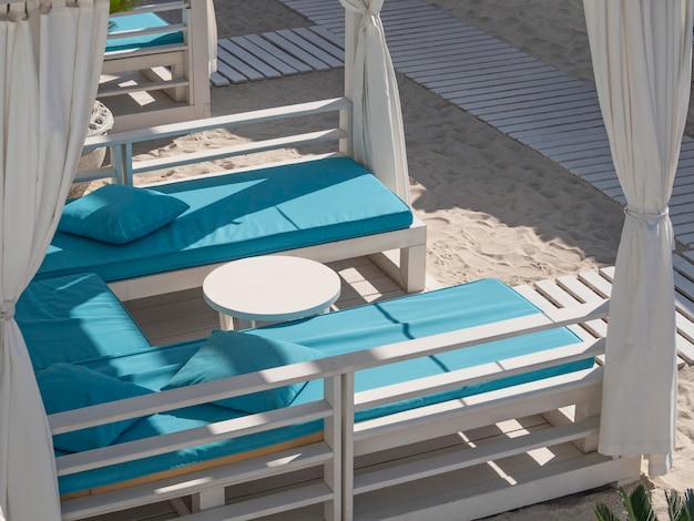 Camas de playa de lujo con mesa y almohadas en balneario