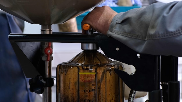 Cambiar el aceite del motor las manos masculinas de un mecánico drenar el aceite viejo del coche en un contenedor especial