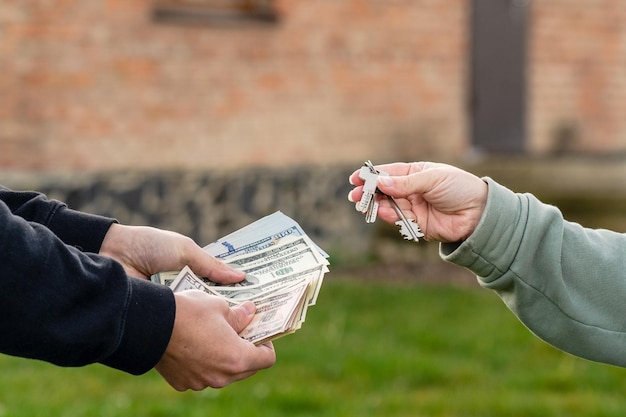 Foto cambio de dinero y llave de casa delante de la casa compra o alquiler de bienes raíces