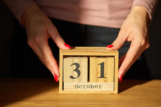 Cambio de mano de mujer establece la fecha en el calendario de madera en octubre