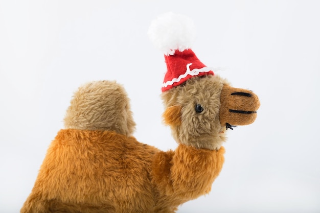 Camello de peluche con sombrero de Santa Claus sobre un fondo blanco. De cerca