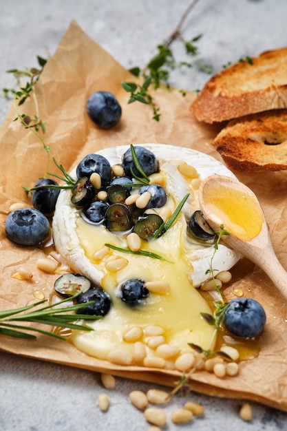 Camembert assado com close-up de especiarias. O queijo é servido com mel, pinhões e mirtilos. Um petisco festivo de vinho gourmet.