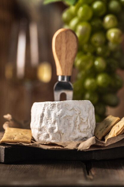 Foto camembert casero orgánico o queso brie sobre una tabla de madera con uvas y nueces y miel. estilo rústico.