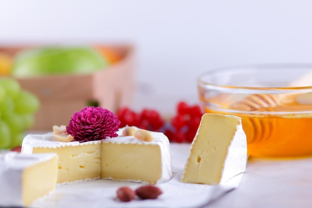 Camembert Französischer Frischkäse aus Kuhmilch, serviert mit Honig und Obst Essen für einen gesunden und leckeren Snack auf weißem Hintergrund Closeup