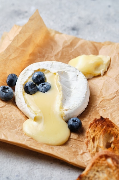 Camembert gebacken mit Gewürzen Nahaufnahme. Der Käse wird mit Honig, Pinienkernen und Blaubeeren serviert. Ein festlicher Gourmet-Wein-Snack.