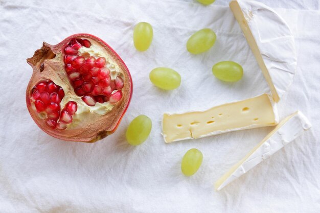 Camembert con granada y uvas verdes en una servilleta blanca Delicioso queso en el primer plano de la mesa Un gran producto para el desayuno