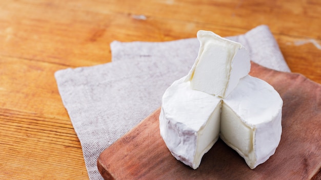 Camembert-Käse auf einem Holzbrett. Weißkäse auf einem hölzernen Hintergrund. Platz kopieren