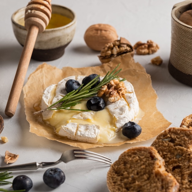 Camembert-Käse auf Papier Heidelbeeren Nüsse Honig Sandwicheson auf grauem Hintergrund Italienisch Französisch