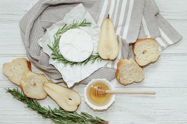 Camembert-Käse mit Birne und Rosmarinzweig mit Honig auf dem Tisch