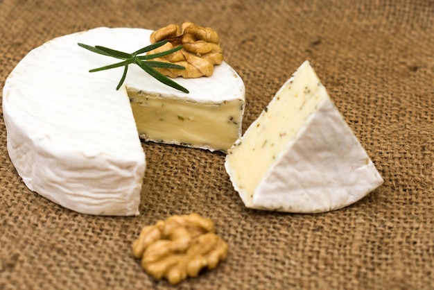 Camembert-Käse mit Kräutern dekoriert mit einem Zweig Rosmarin und Walnuss Closeup