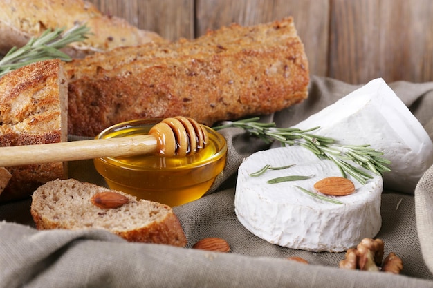 Camembert-Käsehonig und -brot auf Sackleinen in der Schachtel auf dem Tisch auf Holzwandhintergrund