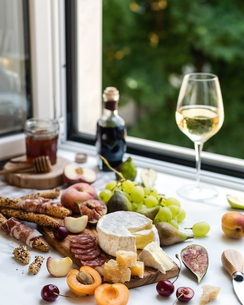 Camembert, Parmesan, Schinken und Obstsorte mit Weißweinglas