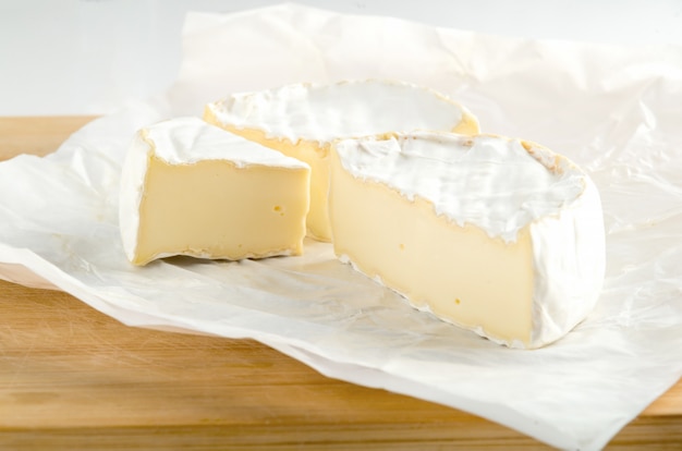 Camembert con pieza sobre papel de regalo blanco.