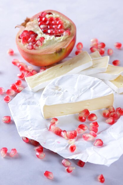 Camembert y semillas de granada sobre papel pergamino sobre un fondo claro Delicioso queso en el primer plano de la mesa Un gran producto para el desayuno