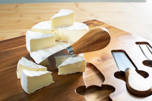 Camembert en una tabla de quesos. Cuchillos para queso. Trozos de Camembert.