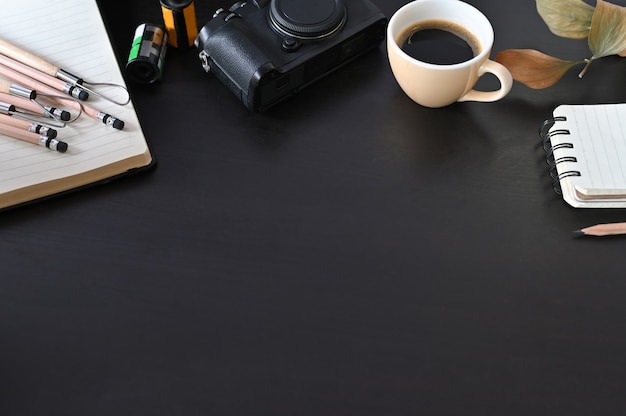 Câmera criativa do local de trabalho, café e papel de nota na tabela preta com foco seletivo.