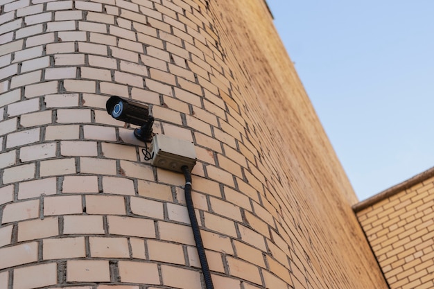 Câmera de vigilância na fachada de um prédio residencial de tijolos. Segurança. Controle sobre a observância da lei e da ordem.