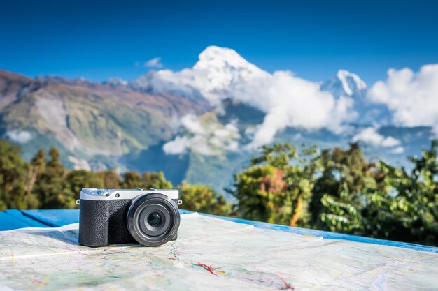 Câmera digital compacta colocada em um mapa em frente ao belo pico coberto de neve da montanha annapurna