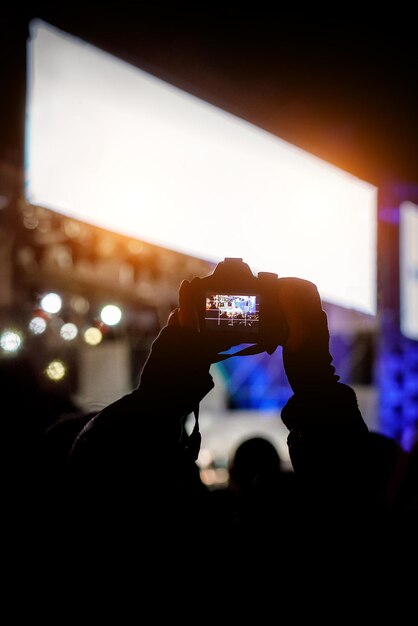 Câmera dslr profissional em concerto de música em cantor de gravação de mão levantada em um palco