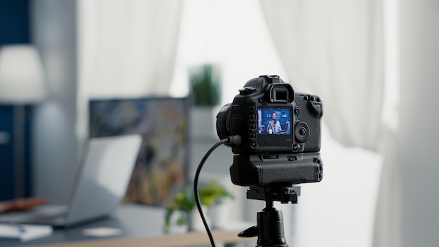 Câmera filmando o criador de conteúdo digital falando ao público. Famosa estrela de mídia social gravando vlog para plataformas de compartilhamento de vídeo enquanto está sentado na mesa do estúdio na sala de estar. Fechar-se