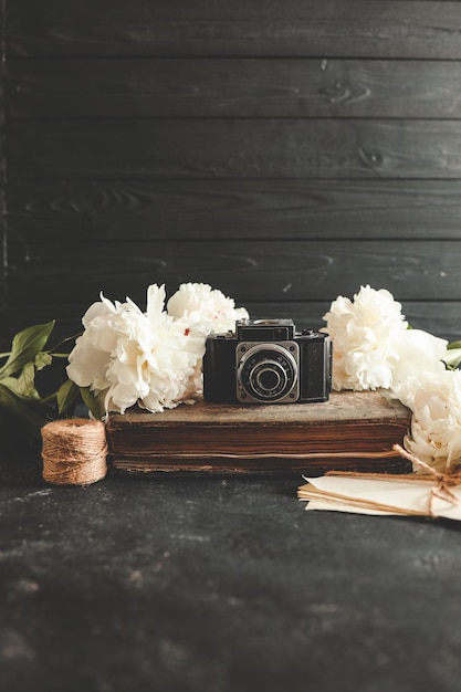 câmera fotográfica retrô com livro e flores frescas de peônia