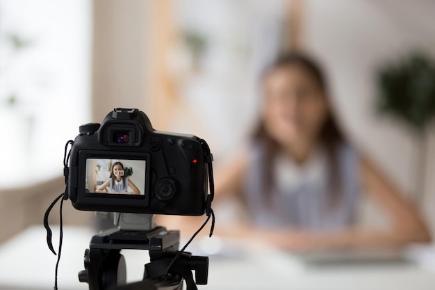 Câmera profissional filmando jovem tutora ou treinadora sorridente fazendo apresentação ou gravando tutorial de master class para vlogger de negócios de mulher de canal filmando treinamento em vídeo para blog ou site