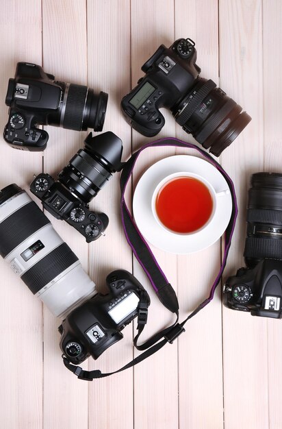 Foto câmeras modernas com xícara de chá em cima da mesa de madeira