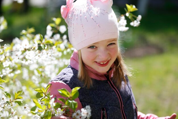 Camina por la calle. Divertida niña preescolar a principios de la primavera cerca del arbusto floreciente