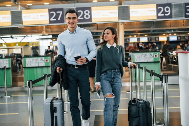 Caminando hacia adelante Pareja joven está en el aeropuerto juntos