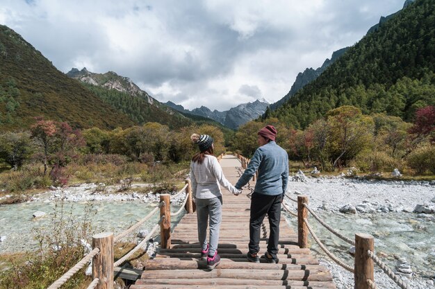 Caminando al viajero joven de la pareja que mira paisaje hermoso en la reserva natural de Yading, concepto de la forma de vida del viaje