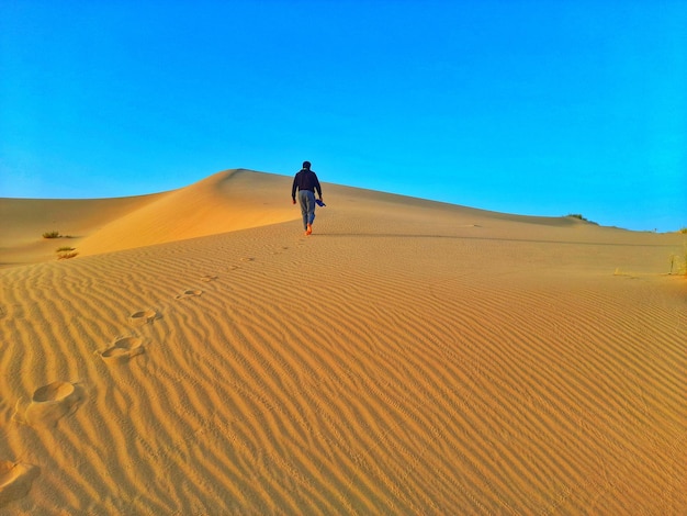 Foto caminando por las dunas de arena en el desierto del sáhara de argelia