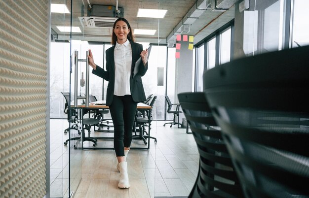 Foto caminando en la oficina la mujer de negocios está en el interior