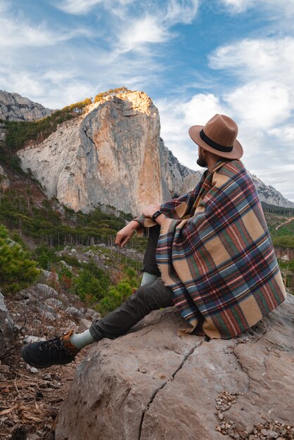 Caminante disfrutando del paisaje con montañas, bosque y cielo. Montañismo y viajes.